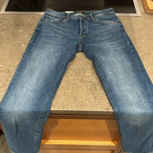 Blå Slim Straight Jeans från Jack & Jones - Säljer ett par snygga blå slim straight jeans från Jack & Jones i modellen Tim. De har en regular rise och smal passform vid lår, knä och benslut. Perfekta för både vardag och fest! 🕺