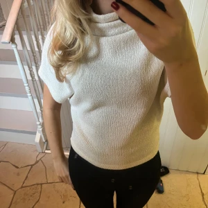 Vit  topp - Säljer en stilren   topp. Perfekt för både vardag och festliga tillfällen. Toppen har en bekväm passform och är gjord i ett mjukt material som känns skönt mot huden. Använd fåtalet gånger