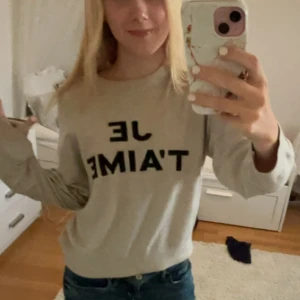 Beige tröja med text - Säljer en beige tröja med texten 'JE T'AIME' i svart. Tröjan är långärmad och har en normal passform. Perfekt för en avslappnad stil och kan matchas med jeans eller kjol. Supermjuk och bekväm för vardagsbruk!