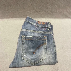 Blå jeans från Dondup - Säljer ett par snygga blå jeans från Dolce & Gabbana. De har en klassisk femficksdesign med slitna detaljer för en trendig look. Perfekta för både vardag och fest! 🕺