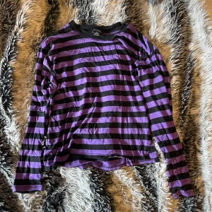 Randig lila och svart tröja - En randig tröja från monki som jag köpt något år sedan men fortfarande bra kvalitet . Den har 2 små slits längs ner på båda sidor . Passar xxs-xs 🖤💜