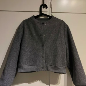 Grå jacka från Vero Moda - Säljer en snygg grå jacka från Vero Moda. Sitter bra på mig som har s i vanligt fall. Jackan har en stilren design med knappar framtill och långa ärmar. Perfekt för höst och vår, och den är i mycket bra skick. Passar både till vardags och lite finare tillfällen.