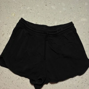 Svarta shorts från H&M - Säljer ett par svarta shorts från H&M i storlek M. De är i mjukt material med elastisk midja och dragsko för justerbar passform. Perfekta för en avslappnad dag eller träning. 🖤