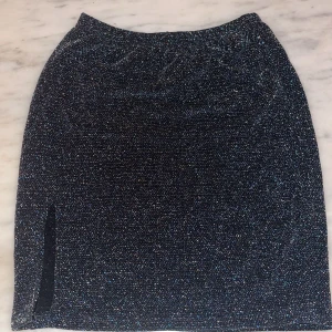 Glittrig kjol från Venderby's - Glittrig kjol från Venderby's i storlek XS/S. Tajt passform men väldigt stretchig. Slutar ovanför knäna. Helt ny, aldrig använd. Nypris ca 400kr.