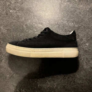 Svarta sneakers från Selected Homme - Säljer ett par stilrena svarta sneakers från Selected Homme i storlek 41. Skorna är i mocka med en vit sula och har klassisk snörning. Perfekta för både vardag och fest! 🖤