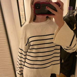 Vit och svart randig tröja - Säljer en supermysig vit tröja med svarta ränder. Den har en oversized passform och långa ärmar, perfekt för höst och vinter. Tröjan är ribbad vid ärmslut och nederkant vilket ger en snygg detalj. Perfekt för en avslappnad stil!