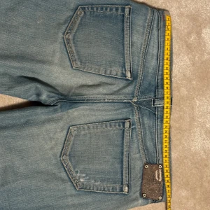 Blå bootcut jeans från Diesel - Säljer ett par snygga blå jeans från Diesel i bra skick. De har en klassisk femficksdesign med en knappgylf och slitna detaljer för en cool look. Perfekta för vardagsbruk eller en avslappnad utekväll. Passar bra med en t-shirt eller hoodie.