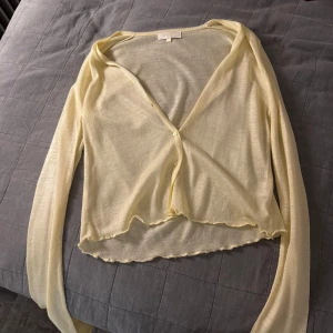 Gul transparent långärmad topp - Säljer en superfin gul transparent topp med långa ärmar. Den har en enkel knapp framtill och en lätt vågig kant nedtill. Oanvänd!!!KOLLA IN DE ANDRA BILLIGA JAG SÄLJER 😉