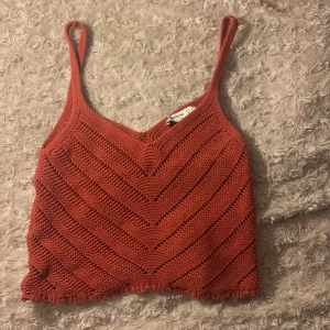 stickad linnetopp från Stradivarius - Säljer en superfin rostfärgad stickad linnetopp från Stradivarius. Toppen har en v-ringad design med smala axelband och ett snyggt mönster. Perfekt för sommardagar eller som ett lager under en jacka. Har använt den ett antal gånger och fick den av min syster men den är fortfarande i bra skick!