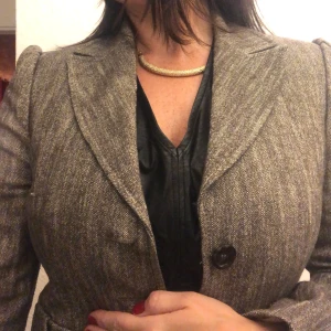 Grå kavaj med knappar - Säljer en stilren grå kavaj i mycket bra skick. Den har en klassisk design med två knappar framtill och långa ärmar. Perfekt för både kontoret och mer formella tillfällen. Passar bra till höst och vår.