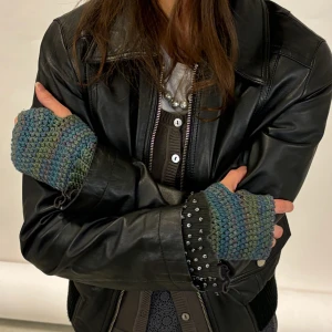 Stickade fingerlösa vantar - Säljer ett par stickade fingerlösa vantar i grönt och blått. Perfekta för höst och vinter när du vill hålla händerna varma men ändå kunna använda mobilen. De har en mysig och bekväm passform med ribbstickade muddar. Perfekt accessoar för en cool och avslappnad stil!