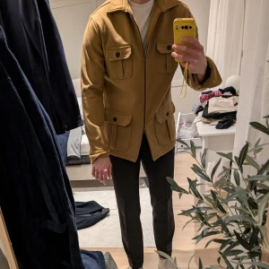 Kamelfärgad overshirt/jacka från John Henric - Säljer en snygg kamelfärgad overshirt från John Henric i mycket bra skick. Jackan har en dragkedja framtill och fyra fickor med knappar, vilket ger den en stilren look. Perfekt för höst och vinter! Passar bra till både vardag och lite finare tillfällen. Storlek L men sitter mer som en M. Jag är 183cm och 77kg på bild.