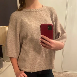 Beige stickad tröja från 157 - Mysig beige stickad tröja från 157 i storlek S. Den har en avslappnad passform med trekvartsärmar och rund halsringning. Perfekt för höst och vår när du vill ha något bekvämt och stilrent. Tröjan är i mycket bra skick och passar till både jeans och kjol.