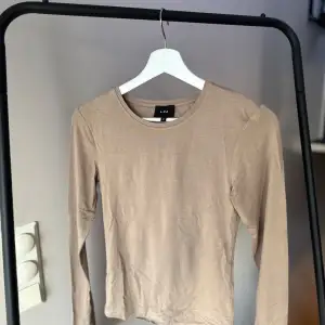 Beige långärmad topp från LXA i storlek M. Perfekt för både vardag och lite finare tillfällen. Toppen är i ett mjukt och bekvämt material. Sparsamt använd, som ny!