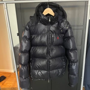 Polo Ralph Lauren glansig dunjacka  - Tjena! Säljer nu denna mörkblåa Ralph Lauren jacka i storlek L. Jackan är i fantastiskt skick utan några defekter. Jackan är varm, snygg och perfekt för vintern. Nypriset för jackan i denna färg ligger på runt 6000kr, jag är villig att sälja den för 4199. PRISET GÅR DOCK ATT DISKUTERAS VID EN SNABB AFFÄR (inga skam bud). Vid några frågor är det bara att höra av sig, jag svarar snabbt!😉