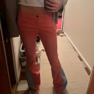 Rosa byxor med grå detaljer - Säljer ett par snygga rosa byxor med grå detaljer längs sidorna. De har en bootcut-stil och är lågmidjade. 