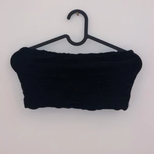 Svart tubtopp - Snygg svart tubtopp i ett mjukt och stretchigt material. Perfekt för sommarens fester eller som ett basplagg i garderoben. Enkel att matcha med både kjol och jeans för en stilren look.