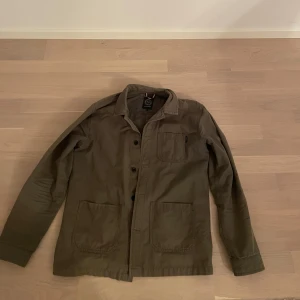Grön overshirt -  Lindbergh - Säljer en snygg grön overshirt från Lindbergh i storlek L. Den är i bra skick men fortfarande använd.