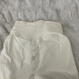 Vita ribbade leggings - Säljer ett par vita ribbade leggings i mycket bra skick. De är högmidjade och har en tight passform som är perfekt för både träning och vardagsbruk. Materialet är mjukt och stretchigt, vilket gör dem superbekväma att ha på sig.🌸används inte längre eftersom dom blivit för små💕💗