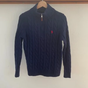 Mörkblå stickad tröja från Ralph Lauren - Säljer en snygg mörkblå stickad tröja från Ralph Lauren med dragkedja och det klassiska röda logotypen på bröstet. Perfekt för kyliga dagar med sin mysiga och stilrena design. Passar både till vardags och lite finare tillfällen. Skulle kunna diskutera priset så hör av er 😇