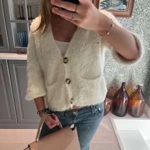 Vit fluffig kofta med stora knappar - Säljer en supermysig vit kofta med stora knappar framtill. Man kan ha den tre kvarts ärmad men även långärmad (de bilder) barn storlek 152 men passar mig som är en xs-s