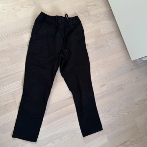 Svarta chinos från Polo Ralph Lauren - Säljer ett par svarta byxor från Polo Ralph Lauren i bra skick. De har en elastisk midja med snörning och två bakfickor med knappar. Perfekta för en avslappnad stil och passar till både vardag och fest. Storleken är stretch classic fit.