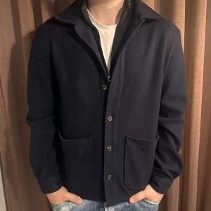 Mörkblå ulljacka från Mango - Säljer en stilren mörkblå ulljacka i mycket bra skick. Jackan har långa ärmar och knappar framtill, perfekt för höst och vår. Den har en klassisk krage och två praktiska fickor. Passar både till vardags och lite finare tillfällen. Skick- 8/10 mycket sparsamt använd. Nypris 1300. Tveka inte på att höra av dig vid frågor/intresse💫