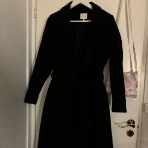 Svart kappa från VILA - Säljer en elegant svart kappa från VILA i storlek 36. Perfekt för höst och vinter med sin stilrena design och långa ärmar. Den har en klassisk passform och är gjord i ett mjukt material som håller dig varm. Ett måste i garderoben för en chic look!