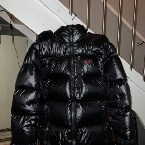 Svart Polo Ralph Lauren jacka  - Säljer en snygg svart pufferjacka från Polo Ralph Lauren i storlek M. Jackan är i mycket bra skick och perfekt för vintern ( använd tiotal gånger). Den har en dragkedja framtill och en liten röd logga på bröstet. Supervarm och stilren för kalla dagar! 🖤❤️