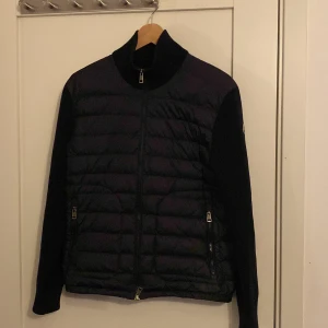 Moncler cardigan  - Säljer en snygg svart jacka från Moncler i bra skick de har en liten skada och de är vid armen kan skicka bild om de frågas. Är även äktighetsverifierad av Garmsmarket 