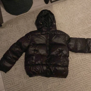 Svart pufferjacka - Säljer en svart pufferjacka i ny skick(testad) från axel luxe. Den är perfekt för kalla vinterdagar med sin tjocka vaddering och långa ärmar. Jackan har en praktisk dragkedja och en huva för extra skydd mot väder och vind. Passar både till vardags och utomhusaktiviteter. Nypris:600 Mitt pris 550. Strl M