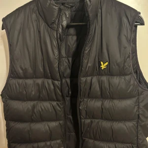 Svart dunväst med broderad logga från lyle and scott. - Säljer en svart dunväst från lyle and scott. Jätte bra skick 