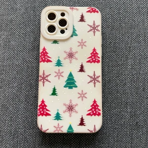 iPhone 12/pro skal mjuk  - Det här är ett mobilskal med juligt tema. Det har ett mönster med gröna och röda julgranar samt snöflingor och stjärnor på en vit bakgrund. Perfekt för att ge din telefon en festlig känsla under julen!