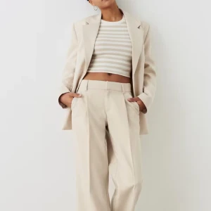 Beige kostymbyxor från Gina Tricot - Säljer ett par snygga lågmidjade kostymbyxor i en elegant sandfärg från Gina Tricot. Byxorna är i storlek S och prislappen sitter fortfarande kvar. Endast provade, aldrig använda. Köpta för 500 kr.  Skick: Nästan nya, men plastknappen i mitten saknas. Detta påverkar inte funktionen, då byxorna fortfarande kan knäppas och sitter som de ska. Om man vill, går det enkelt att fixa plastknappen själv