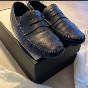 Blåa loafers från Gucci - Säljer ett par stilrena blåa loafers från Gucci i skinn. Skorna har ett diskret mönster och är i mycket bra skick. Perfekta för både vardag och fest. Kommer med originalförpackning och dust bags 