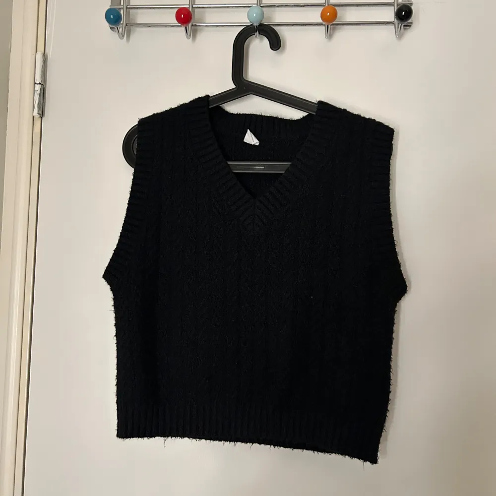 Snygg svart stickad väst från Lindex med v-ringad design. Perfekt för lager-på-lager under kyligare dagar. Enkel och stilren, passar till många olika outfits.. Neuleet.