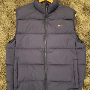 Blå dunväst från Tommy Hilfiger - Tja, säljer nu denna feta vest eftersom ja inte längre använder den. Inget fel på den 10/10, storlek M. Modellen på bilden är ca 185, priset är absolut inte skrivet i sten så det är bara att skicka t mig/cheffen🤠