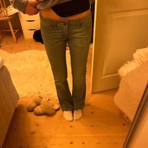 Blå jeans från Wrangler - Snygga ljusblå jeans från Wrangler med en klassisk femficksdesign. De har en bootcut passform och är perfekta för en avslappnad stil. Jeansen har en låg midja och är tillverkade i ett slitstarkt material. Helt nya aldrig använda. Så snygg detalj på bakfickan! Passar mig som är 167