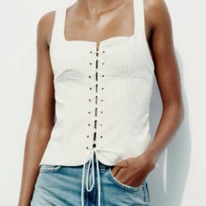 Vit  korsettopp - Snygg vit ribbad korsettopp med snörning framtill och en dragkedja bak för enkel påklädning💕💕 Aldrig använd så den är som ny! Perfekt för en stilren look.