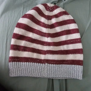 Randig mössa från Esprit - Snygg randig mössa från Esprit i vinrött och vitt med en silver ribbad kant. Perfekt för kyliga dagar med sin stickade design. Mössan har en liten logotypdetalj i metall.