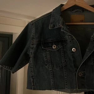 Blå croppad jeansjacka - Säljer en trendig blå croppad jeansjacka med korta ärmar (jag har klippt den själv) och knappar framtill. Perfekt jacka att ha på sommaren!