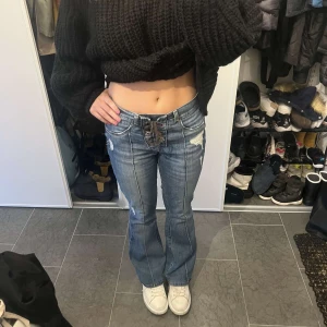 Blå bootcut jeans med snörning - Snygga blå bootcut jeans med cool snörning framtill. De har slitna detaljer och e as coola passar mig som är 168