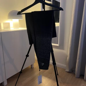 Svarta och grå leggings från Gymshark - Snygga svarta och grå leggings från Gymshark med en ombre-effekt. Perfekta för träning med en tight passform och hög midja. Strl XL men mer som en L. Nypris 599:-