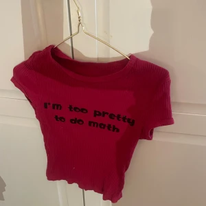 Röd ribbad t-shirt med tryck - Säljer en röd ribbad t-shirt med texten 'I'm too pretty to do math' på framsidan. T-shirten har korta ärmar och en rund halsringning. Perfekt för en avslappnad stil.