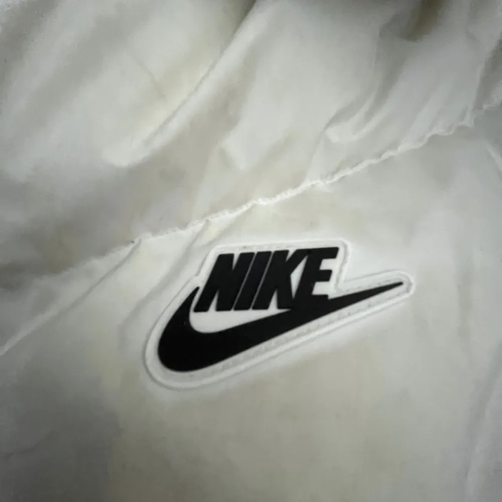 Snygg och varm dunjacka från Nike i svart och vitt. Jackan har en huva och dragkedja framtill. Perfekt för kyliga dagar.. Takit.