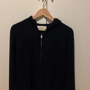 Marinblå cashmere hoodie från Sayles - Snygg och bekväm svart hoodie i mjuk cashmere från Sayles. Tröjan har en dragkedja framtill och en praktisk huva med snörning. Perfekt för kyliga dagar.