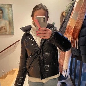 Svart pufferjacka från Calvin Klein Jeans - Snygg svart pufferjacka från Calvin Klein Jeans. Jackan har en glansig finish och dragkedja framtill. Perfekt för kyliga dagar med sin vadderade design och höga krage. Pris kan diskuteras. Nypris:2500