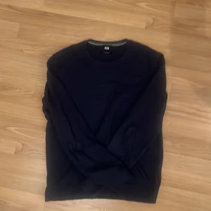 Mörkblå tröja från WE - Säljer en stilren mörkblå tröja från WE i bomull. Tröjan har en klassisk rund hals och långa ärmar, perfekt för en avslappnad look. Den är tillverkad i 100% bomull och nypris ligger på 490kr.