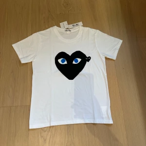 Vit CDG tshirt, Svart/blå : Nysick - Snygg vit t-shirt från Comme des Garçons Play. Aldrig andvänd och aldrig tvättad, riktigt stilren, och ja kvitto fins 🧾✅. Lite mindre i storleken, hör av er vid frågor