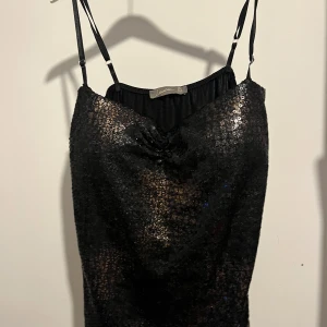 Svart och brun paljett topp med smala axelband - Snygg svart topp med glittrande paljetter och smala axelband. Perfekt för en kväll ute. 